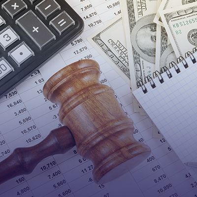 Richterholzhammer, Taschenrechner, Dollarscheine und Dokumente auf dem Tisch | Johann Richter Steuerberater